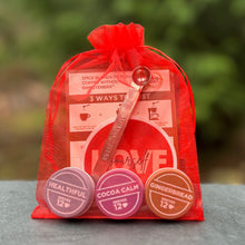 Load image into Gallery viewer, Love Brews Magic set - Healthful, Gingerbread, Cocoa Calm, spoon, sticker and card in a red mesh bag